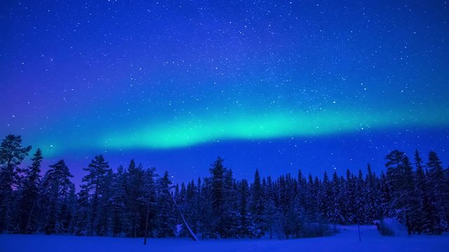 Lapland. Night. Winter forest. Starry sky and Northern Lights. Time lapse