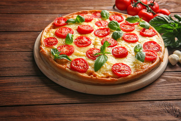 Fresh tasty pizza Margarita and tomatoes on wooden background