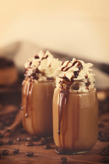 Glass jars with delicious milk dessert and coffee beans on table, closeup