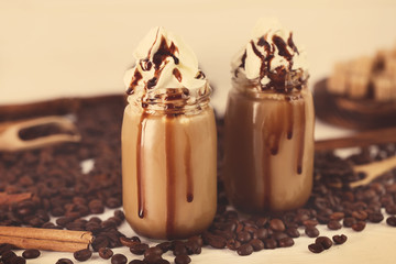 Glass jars with delicious milk dessert and coffee beans on table, closeup