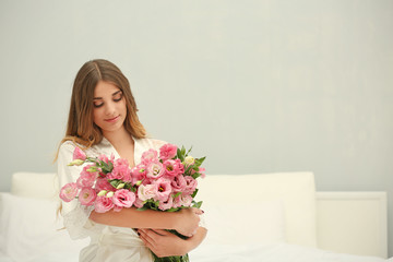Pretty girl in bedroom with big bouquet of flowers