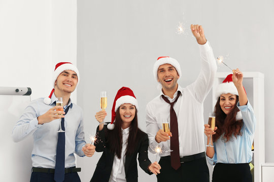 Business people in Santa hats with sparklers at office party