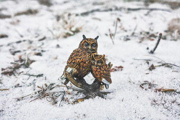 figure owl with nestling on a tree stump in snow
