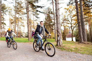 Obraz premium Young family in warm clothes cycling in autumn park