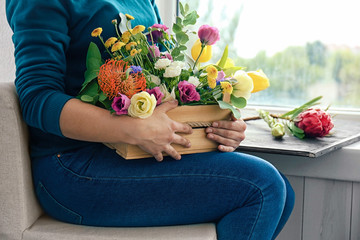 Female florist holding beautiful flower composition in box, closeup