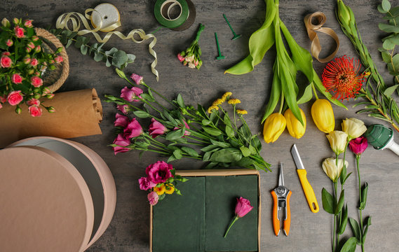 Beautiful flowers with boxes and florist equipment on dark background