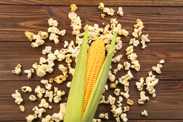 Fresh maize and popcorn on wooden background