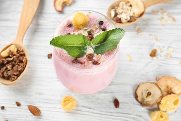 Healthy and tasty breakfast of berry milkshake with dry fruits and mint on wooden table