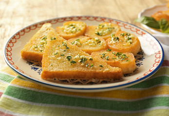 Plate with tasty garlic French bread slices on wooden table