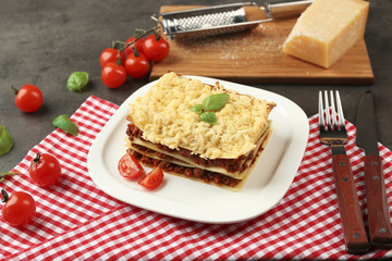 Plate with portion of tasty lasagna on napkin