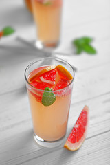 Glass of refreshing grapefruit drink on table