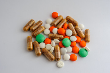 composition of white pills and brown capsule orange dragee and green tablets