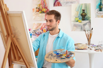 Young male artist painting picture in studio