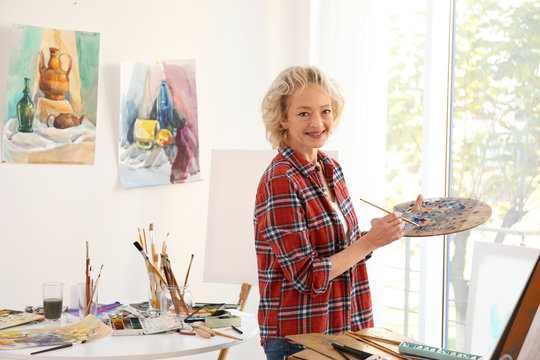 Senior female artist with palette and brush in studio