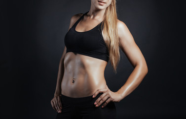 Fototapeta na wymiar Muscular fitness woman posing on a dark background in studio
