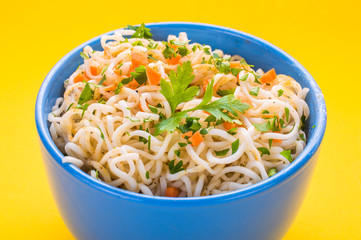 Bowl of instant noodles on yellow background.