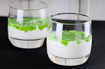 Fruit dessert green panna cotta in a glass over black background