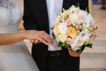 Obraz na płótnie Canvas Bride and groom's hands with wedding rings on brown table