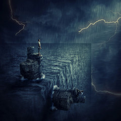 Conceptual image with a lost man sitting on a rock cliff island, in the middle of the ocean, try to...