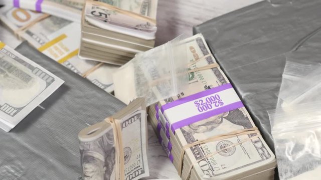 Cocaine bricks and bags with money on a table. Panning shot top view.