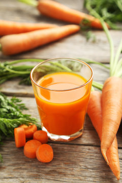 Fresh carrot juice in glass on a grey wooden table