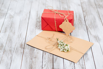 Greeting letter and gift box with tag on wooden background.
