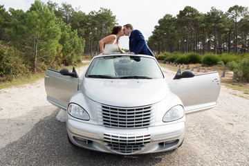 Beautiful wedding couple posing near splendid cabriolet car