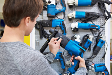 Man shopping for hammer drill in hardware store
