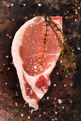 pork loin steak with thyme, peppercorn and coarse salt on an roa