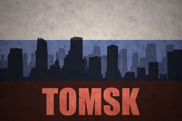 abstract silhouette of the city with text Tomsk at the vintage russian flag