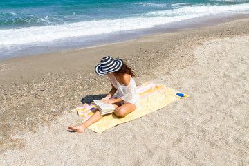 Obraz premium Beautiful stress free woman reading a book at the beach