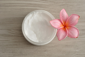 Body lotion in a container with a pink frangipani flower