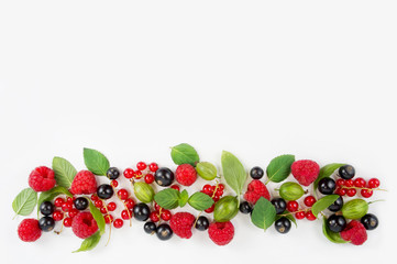 Various fresh summer berries. Ripe raspberries, currants, gooseberries, mint and basil leaves. Berries on white background. Top view