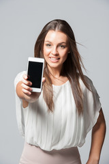 Fototapeta premium Portrait of smiling young business woman holding a phone