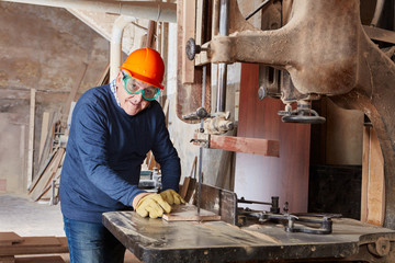 Senior sägt Holz an Bandsäge