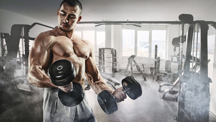 Sport and fitness. Muscular bodybuilder in the gym training with dumbbells