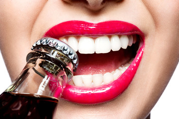 Closeup of beautiful female lips red with white teeth, opening the cork of the bottle with soda