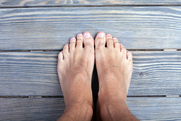 male feet on wooden background.