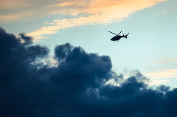 Silhouetted Helicopter Flying Across a Sunset Sky