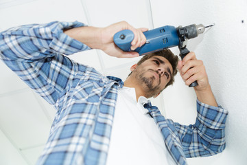 male builder drilling holes in wall at construction site