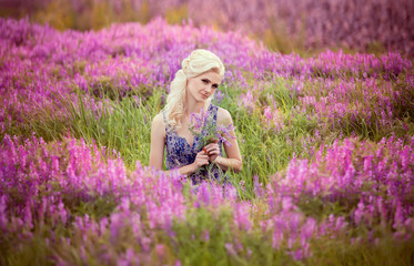 Beautiful blonde girl in a field of lavender flowers.