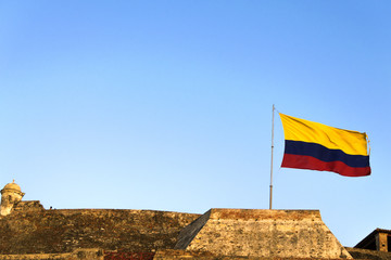 colombian flag being move by the wind over sky and clouds on a sunny day.