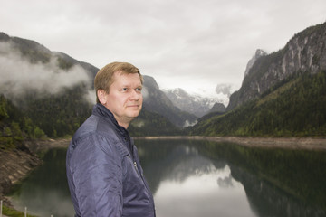 Fototapeta premium A traveler on the background of an alpine lake Gosausee in cloudy weather, Austria 