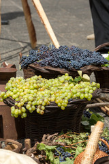 bunches of white and black grapes in a wicker basket.
