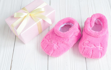 baby's bootees and gift box on wooden background