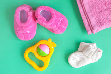 children's clothes and baby booties on green background