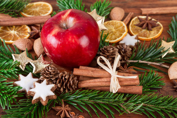 Red apple with christmas spices and fir branch on wooden background