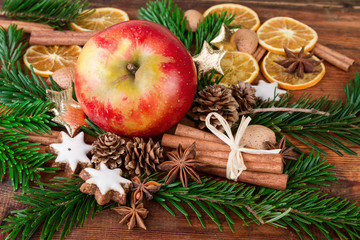 red apple with christmas spices and fir branch on dark wood