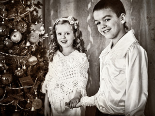 Fototapeta na wymiar Black and white picture children under Christmas tree. Christmas retro style. Old picture. Brother and sister meet Christmas.