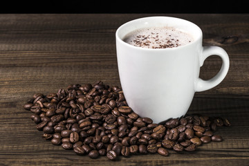 cup of coffee with coffee beans on wooden table. Image with copy space